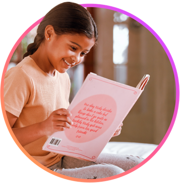 A young girl smiling and reading a book