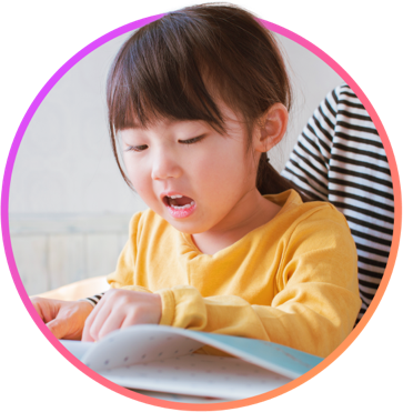 A young girl sounding out words as she reads a book with an adult